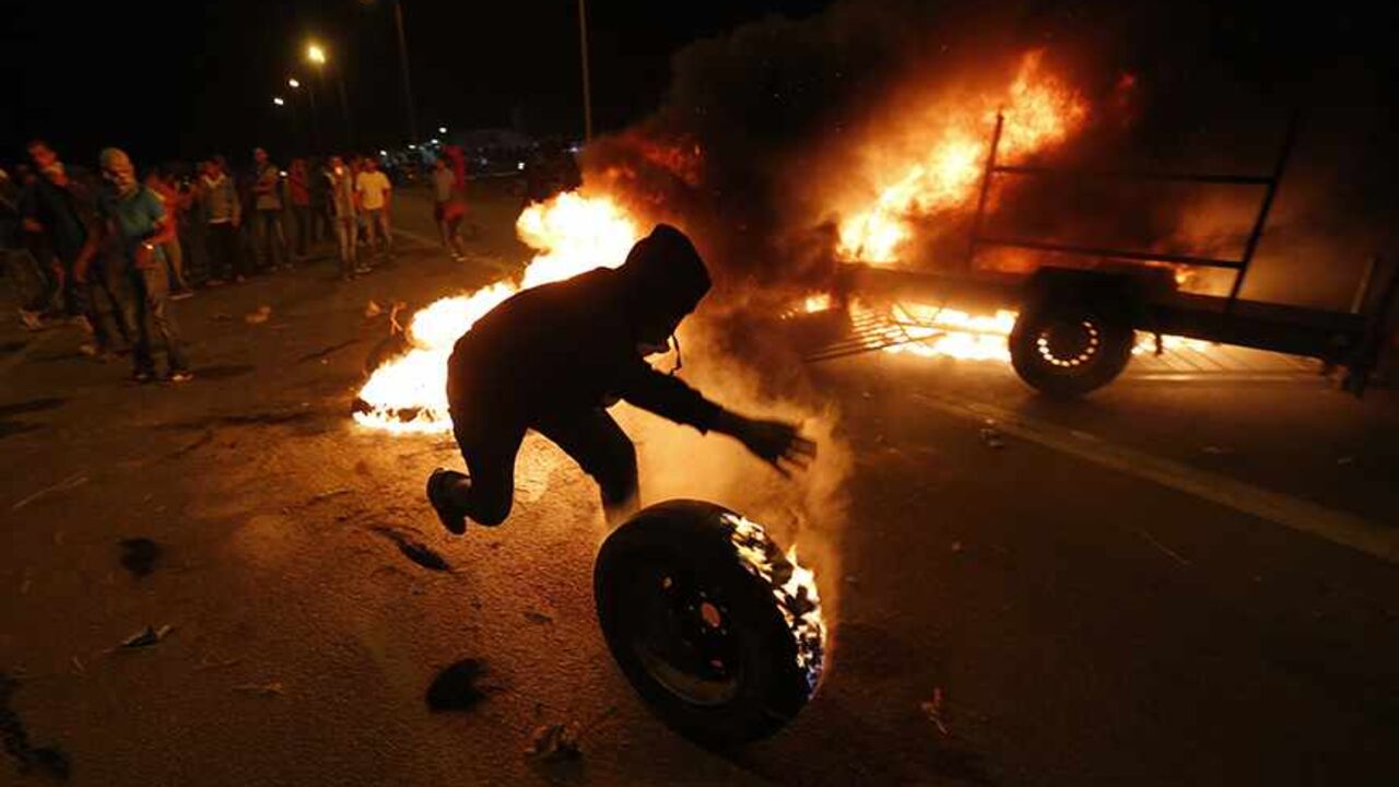 ISRAEL-BEDOUIN/ A protester rolls a burning tyre towards Israeli police during a demonstration showing solidarity with Bedouin Arabs who are against a government displacement plan for Bedouins in the Southern Negev desert in the village of Hura in southern Israel November 30, 2013. REUTERS/Baz Ratner (ISRAEL - Tags: CIVIL UNREST POLITICS TPX IMAGES OF THE DAY) - RTX15YV8