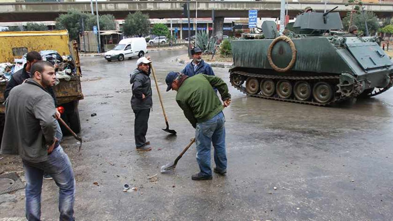 LEBANON-TRIPOLI/ARMY People clean the streets as the Lebanese army deploys on the streets of the Sunni Muslim Bab al-Tebbaneh neighbourhood in Tripoli, northern Lebanon December 4, 2013. The Lebanese government has told the army to take over security in the restive coastal city of Tripoli for six months, caretaker Prime Minister Najib Mikati said on Monday. Ten people were killed in weekend clashes between Tripoli's Alawite minority, which supports Syria's Alawite President Bashar al-Assad, and majority Sunni Muslims who back h