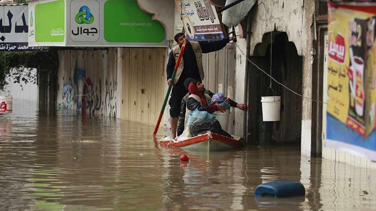 PALESTINIANS-GAZA/WEATHER Palestinians man a boat carrying food supplies, to be passed to people whose houses were flooded with rainwater on a stormy day, in the northern Gaza Strip December 14, 2013. Northern Gaza Strip has become a disaster area following an icy storm that led to the evacuation of hundreds of Palestinian families from their flooded houses to UNRWA facilities, Chris Gunness, UNRWA spokesman, said. REUTERS/Mohammed Salem (GAZA - Tags: ENVIRONMENT SOCIETY TPX IMAGES OF THE DAY) - RTX16HYD