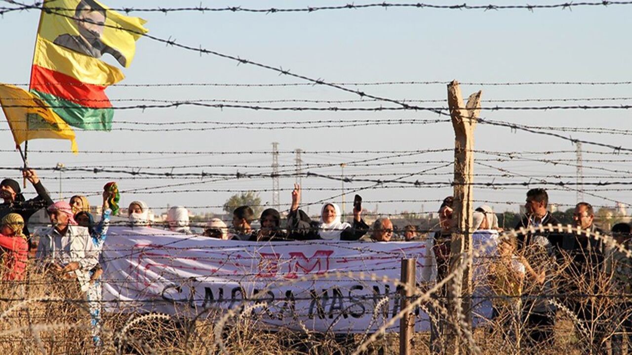 Par7690353 Syrian Kurds wave a flag depicting PKK's (Kurdish Workers Party) jailed leader Abdullah Ocalan as they gather on the border with Turkey, near Mardin's Nusaybin district, on October 20, 2013. Kurdish people protest against the construction by the Turkish government of a 2.5-kilometer-long wall along the border between Turkey and Syria. AFP PHOTO/ MEHMET ENGIN (Photo credit should read MEHMET ENGIN/AFP/Getty Images)