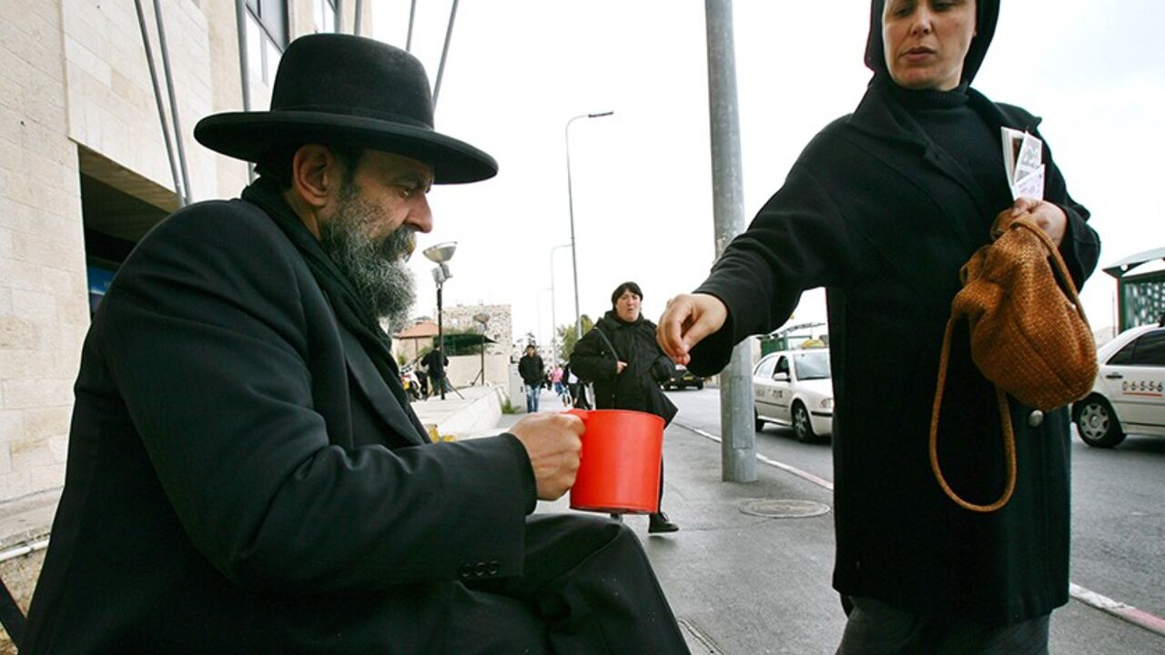 MIDEAST An Ultra-Orthodox Jewish man begs for change as he sits on a sidewalk in Jerusalem March 26, 2006. A growing number of Israelis live beneath the poverty line, many of them ultra-Orthodox Jews, immigrants and elderly. Poverty is a prominent issue in Israel's campaign for a March 28 parliamentary election. Picture taken march 26, 2006. REUTERS/Ronen Zvulun - RTR17NNS