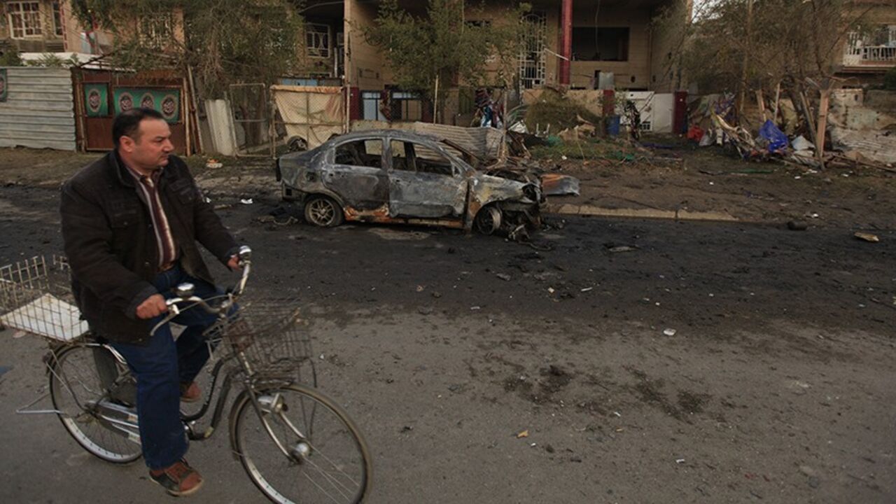 IRAQ-VIOLENCE/ A man on his bicycle passes near the site of a car bomb attack in Baghdad, January 14, 2014. Four car bombs killed at least 25 people in Shi'ite Muslim districts of Baghdad on Monday, police said, in violence that coincided with a visit to the Iraqi capital by U.N. Secretary-General Ban Ki-moon. Although no group claimed responsibility, the bombings appeared to be part of a relentless campaign by al Qaeda-linked Sunni Muslim militants to undermine Prime Minister Nuri al-Maliki's Shi'ite-led government. REUT