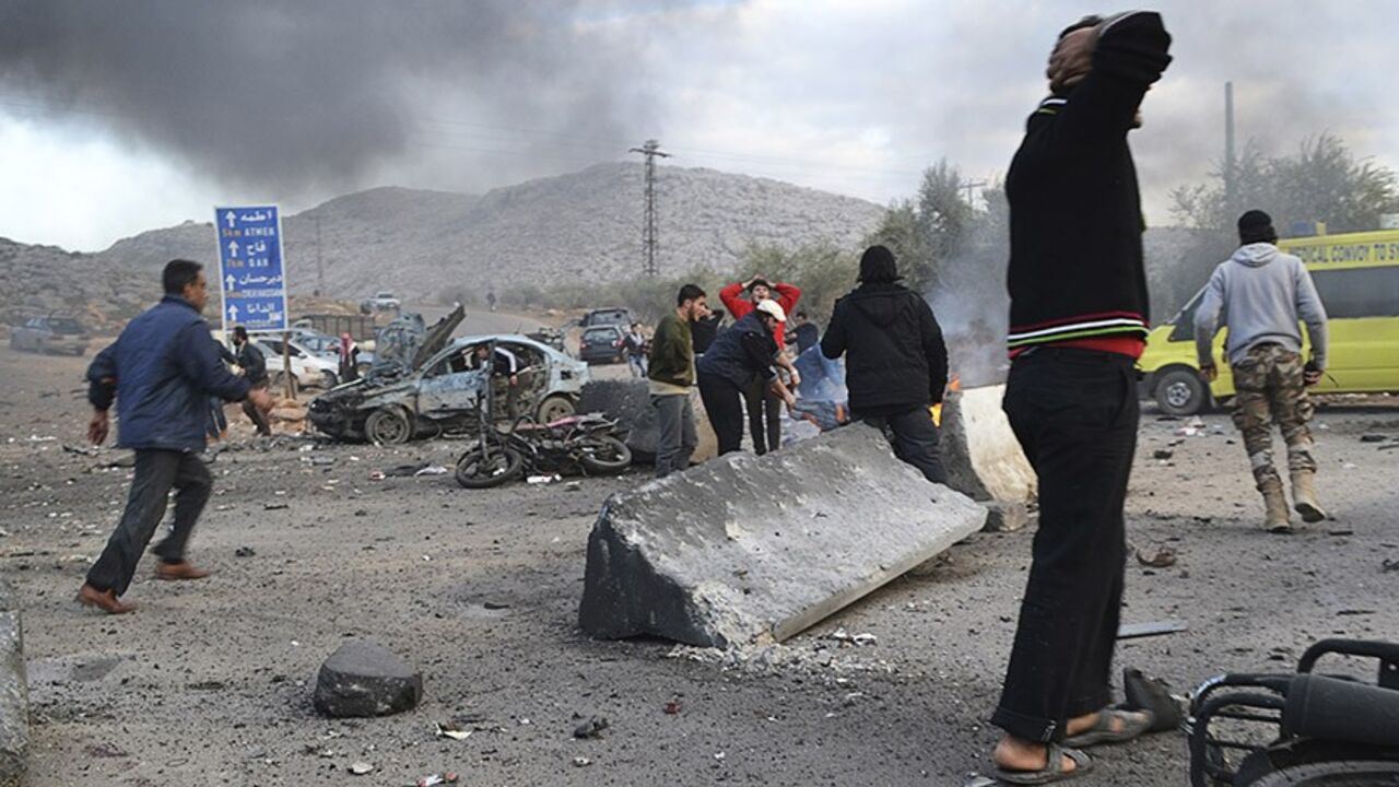 SYRIA-CRISIS/BOMB Men react as others rush at the site of a car bomb attack at the Bab al-Hawa border crossing between Syria and Turkey, in Idlib January 20, 2014. Two car bombs hit a rebel-held border post in the northwest Syrian province of Idlib on Monday, opposition activists and fighters said, killing at least 10 people and closing the frontier. The Bab al-Hawa crossing is held by a rebel alliance called the Islamic Front, which have been fighting with the al Qaeda-linked Islamic State in Iraq and the Levant (ISIL), a s