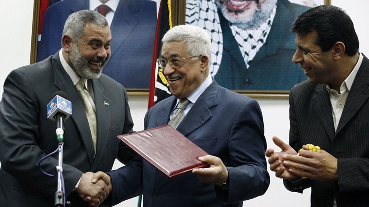 Palestinian President Mahmoud Abbas (C) gives the letter of appointment to Prime Minister Ismail Haniyeh (L) as senior Fatah leader Mohammed Dahlan watches in Gaza February 15, 2007. Abbas formally asked Haniyeh of Hamas on Thursday to form a new unity government and urged him to abide by peace accords signed with Israel. REUTERS/Suhaib Salem (GAZA) - RTR1MG8X