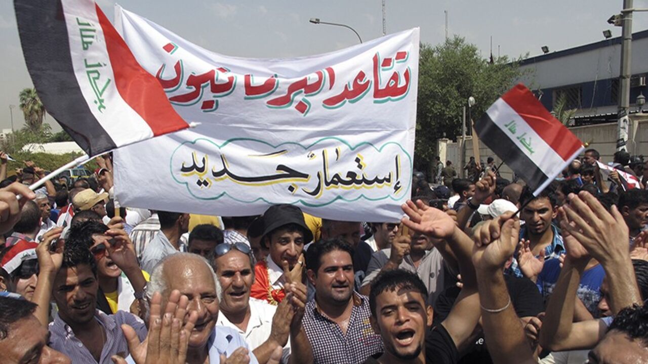 IRAQ/ Protesters hold a banner that reads "Retired parliamentarians neo-colonialism" during a demonstration demanding that the pensions of parliamentarians be cancelled in Baghdad, August 31, 2013. REUTERS/Thaier al-Sudani (IRAQ - Tags - Tags: POLITICS BUSINESS EMPLOYMENT SOCIETY CIVIL UNREST) - RTX132E5