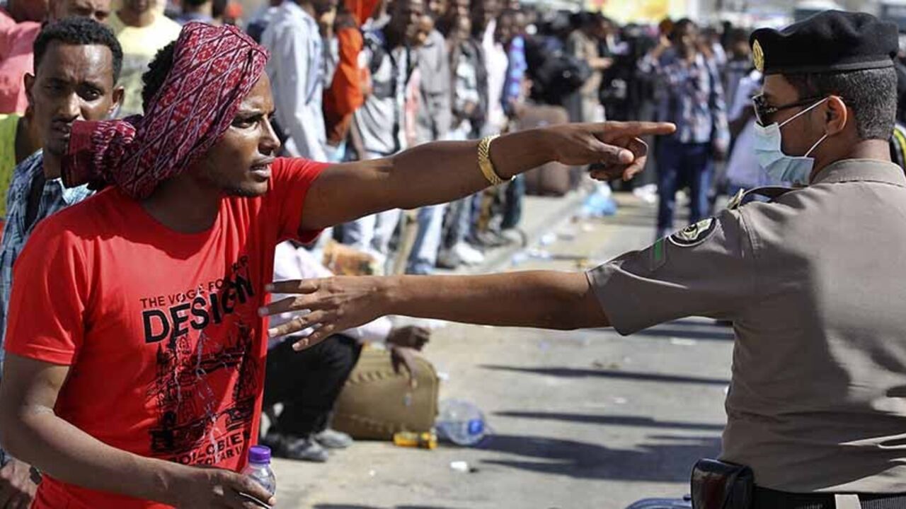 SAUDI-FOREIGNWORKERS/RIOT An Ethiopian worker argues with a member of the Saudi security forces as he waits with his countrymen to be repatriated in Manfouha, southern Riyadh, November 11, 2013. Thousands of mostly African workers gathered in Riyadh on Sunday seeking repatriation after two people were killed in overnight rioting that followed a visa crackdown by Saudi authorities. One of those killed was a Saudi, said a government statement, and the other was not identified. An Ethiopian man was killed in a visa raid last week. Ethi