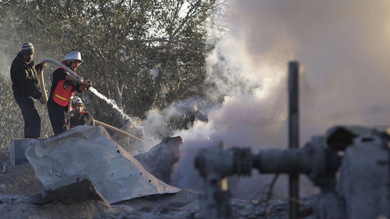 A member of Palestinian civil defense extinguishes a fire at a Hamas training camp after it was hit by an Israeli air strike in Khan Younis in the southern Gaza Strip December 24, 2013. A Gaza sniper shot dead an Israeli civilian over the border on Tuesday and Israel hit back with air strikes on two Hamas training camps which hospital officials said killed a Palestinian girl near one of the targets. REUTERS/Ibraheem Abu Mustafa (GAZA - Tags: POLITICS CIVIL UNREST) - RTX16TBF