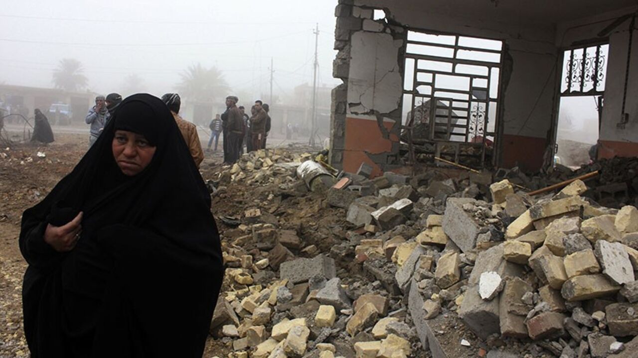 IRAQ-VIOLENCE A woman walks past the site of a bomb attack in Balad Ruz, in northeastern Iraq, January 3, 2014. A suicide bomber driving a car packed with explosives killed at least 12 people who had gathered to buy and sell cars in Iraq on Thursday, local officials said. No group immediately claimed responsibility for the attack, which took place near the car markets in the town of Balad Ruz, in northeastern Iraq, injuring another 25 people. REUTERS/Mohammed Adnan (IRAQ - Tags: CIVIL UNREST) - RTX170P9