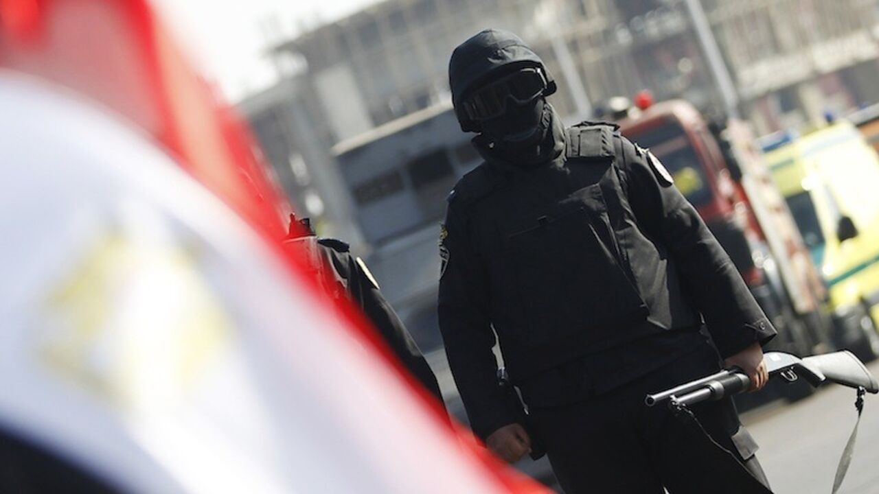 A member of the security forces stands guard outside a police academy, where the trial of ousted Egyptian President Mursi and members of the Muslim Brotherhood is due to take place, on the outskirts of Cairo A member of the security forces stands guard near a national flag outside a police academy, where the trial of ousted Egyptian President Mohamed Mursi and members of the Muslim Brotherhood is due to take place, on the outskirts of Cairo, January 28, 2014. Mursi went on trial at a Cairo police academy on Tuesday on charges in connection with a mass jail break during the 2011 uprising, state television reported. REUTERS/Amr Abdallah Dalsh (EGYPT - Tags: POLITICS CRIME LAW CIVIL UNREST) - RTX17Y5A