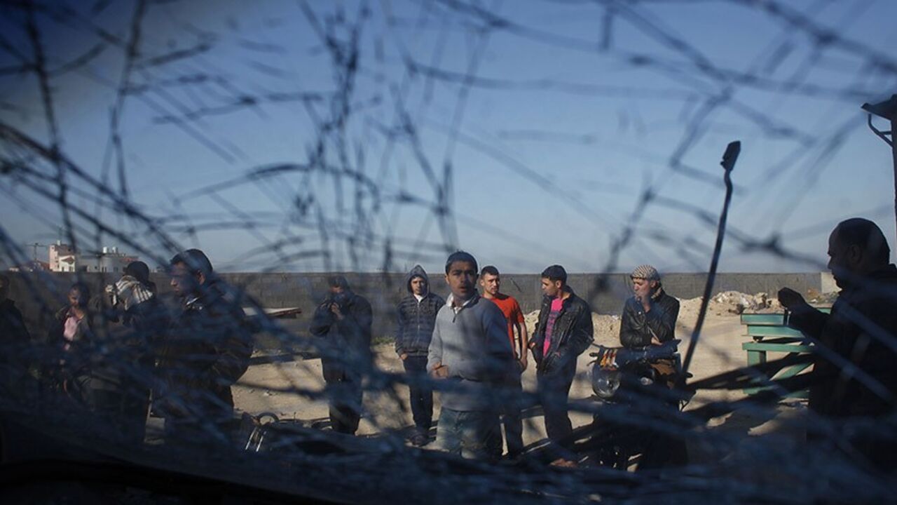 PALESTINIANS-ISRAEL/GAZA Palestinians are seen through a damaged car window as they look at the scene of an Israeli air strike in the centre of the Gaza Strip February 9, 2014. An Israeli air strike on the Gaza Strip on Sunday critically wounded a Palestinian whom the military said was responsible for launching rockets at southern Israel. REUTERS/Ibraheem Abu Mustafa (GAZA - Tags: POLITICS CIVIL UNREST TPX IMAGES OF THE DAY) - RTX18GBQ