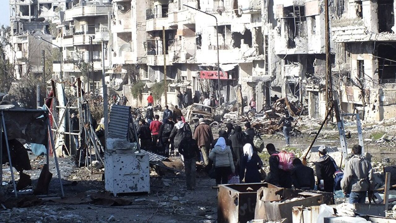 SYRIA-CRISIS/HOMS Civilians carry their belongings as they walk towards a meeting point to be evacuated from a besieged area of Homs February 9, 2014. Six hundred people left the besieged ruins of rebel-held central Homs on Sunday, escaping more than a year of hunger and deprivation caused by one of the most protracted blockades of Syria's devastating conflict. The evacuees, mainly women, children and old men, were brought out by the United Nations and Syrian Red Crescent on the third day of an operation during which the aid