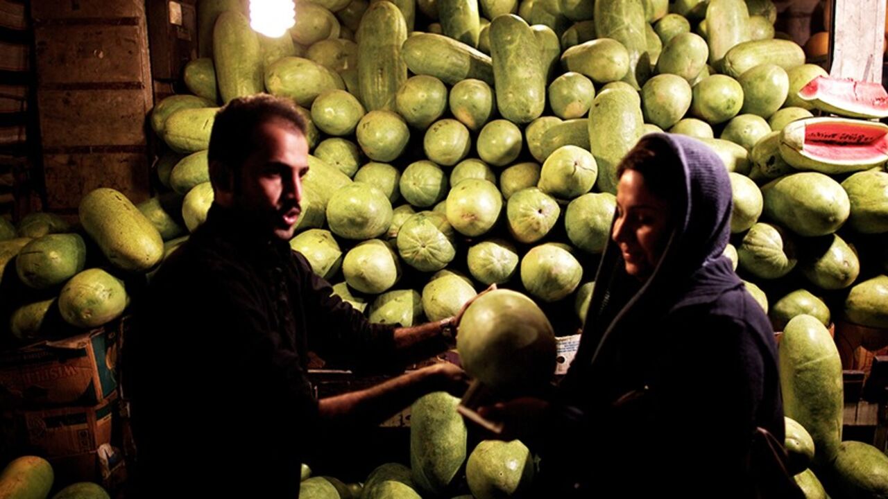 Nic6277696 An Iranian woman buys a watermelon in downtown Tehran on December 21, 2013, in preparation for the annual festival of Yalda, an ancient Zoroastrian rite held on the longest night of the year or the beginning of winter. The rite, which marks the victory of Good over Evil, is still celebrated by most Iranians even though Islam replaced Zoroastrianism as the official religion in the seventh century. Iranians traditionally spend Yalda at home with their families, reciting poetry and feasting on fruits and nuts.