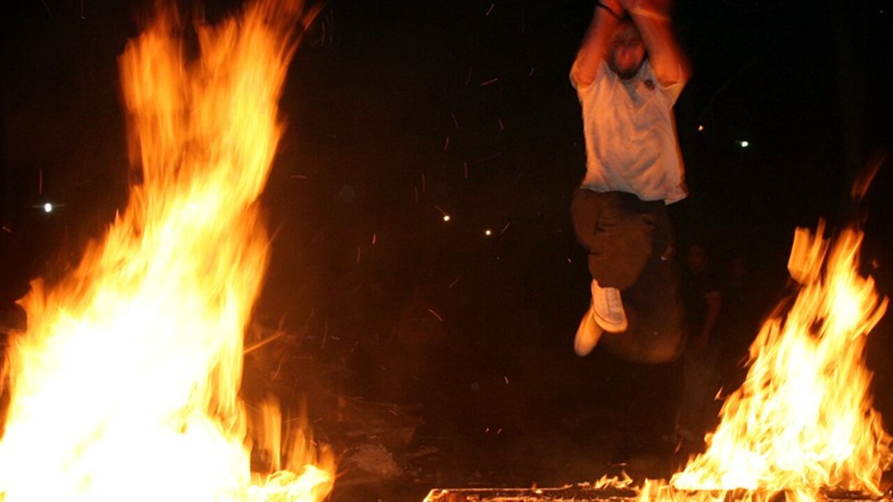 IRAN An Iranian man jumps over a fire to mark the last Tuesday of the Iranian calendar year in Tehran, Iran March 14, 2006. REUTERS/Morteza Nikoubazl - RTR175XZ