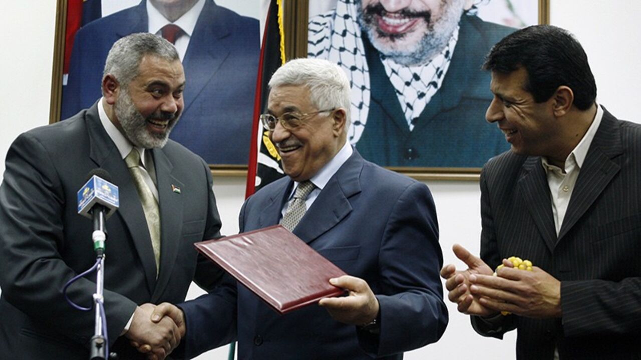 PALESTINIANS/ Palestinian President Mahmoud Abbas (C) gives the letter of appointment to Prime Minister Ismail Haniyeh (L) as senior Fatah leader Mohammed Dahlan watches in Gaza February 15, 2007. Abbas formally asked Haniyeh of Hamas on Thursday to form a new unity government and urged him to abide by peace accords signed with Israel. REUTERS/Suhaib Salem (GAZA) - RTR1MG8X