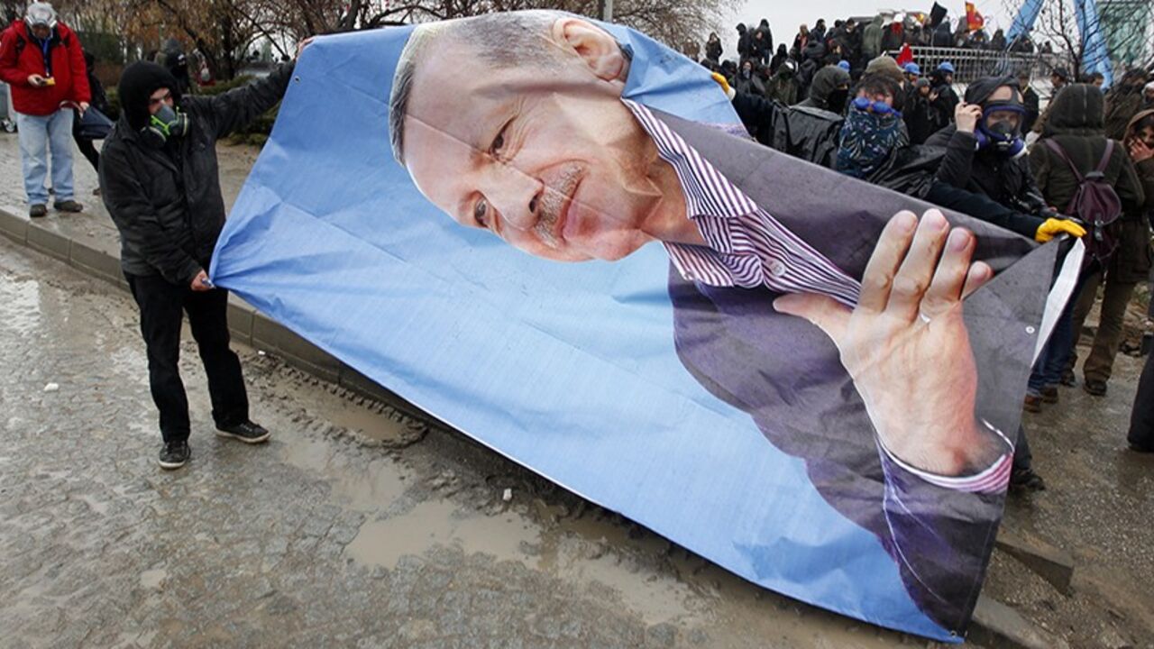 TURKEY/ Protesters seize a portrait of Turkey's Prime Minister Tayyip Erdogan during a demonstration against the opening of a new road include a part of the Middle East Technical University campus in Ankara February 25, 2014. Erdogan opened the road across the Middle East Technical University campus and uprooting a large number of trees in the area in Ankara on Tueasday. REUTERS/Umit Bektas (TURKEY - Tags: POLITICS CIVIL UNREST) - RTR3FPP6