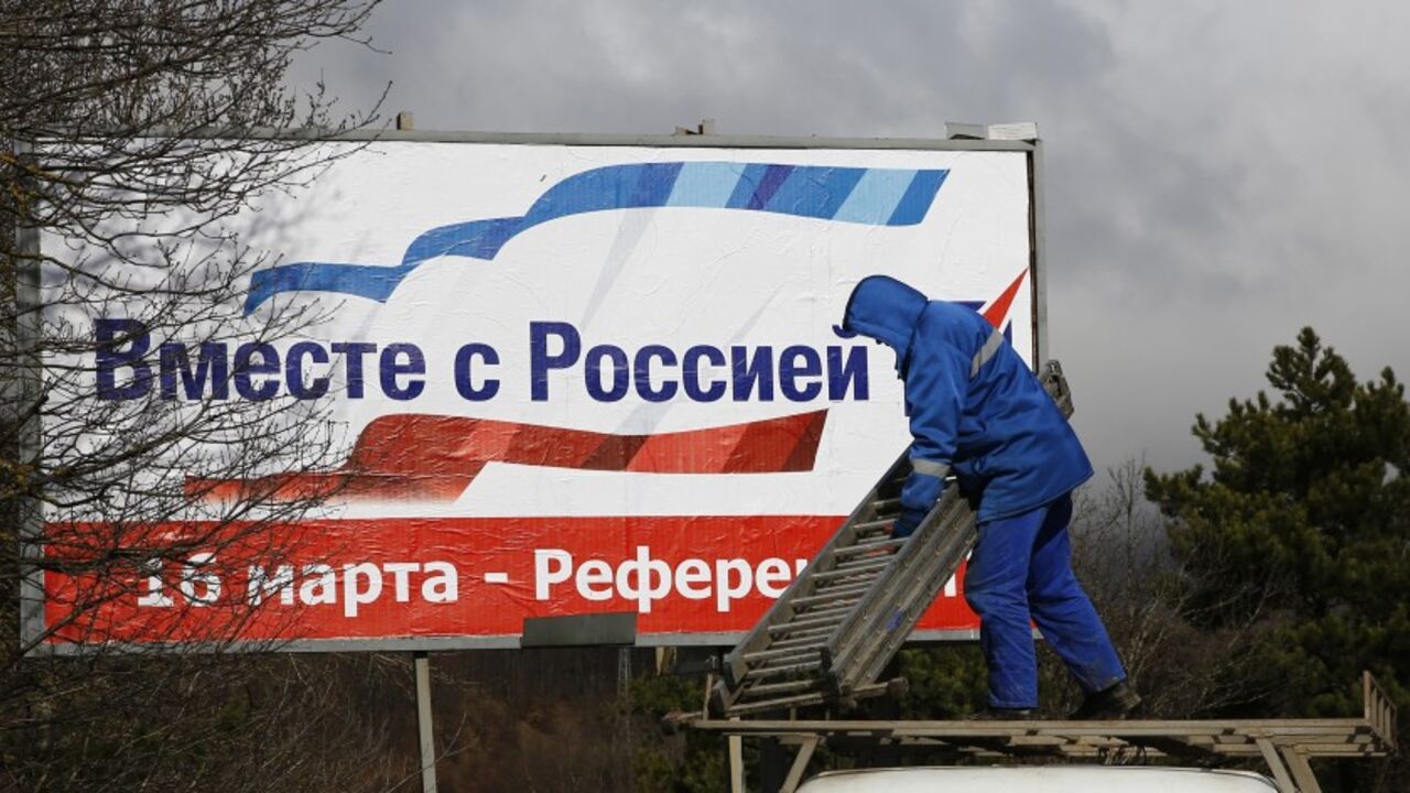 UKRAINE-CRISIS/ A man puts up a poster calling on Crimea residents to vote in favour of the Ukrainian peninsular joining the Russian federation, at a highway outside of Simferopol March 11, 2014. The poster reads, "Together with Russia. March 16 - referendum". REUTERS/Thomas Peter (UKRAINE - Tags: POLITICS ELECTIONS) - RTR3GNOI