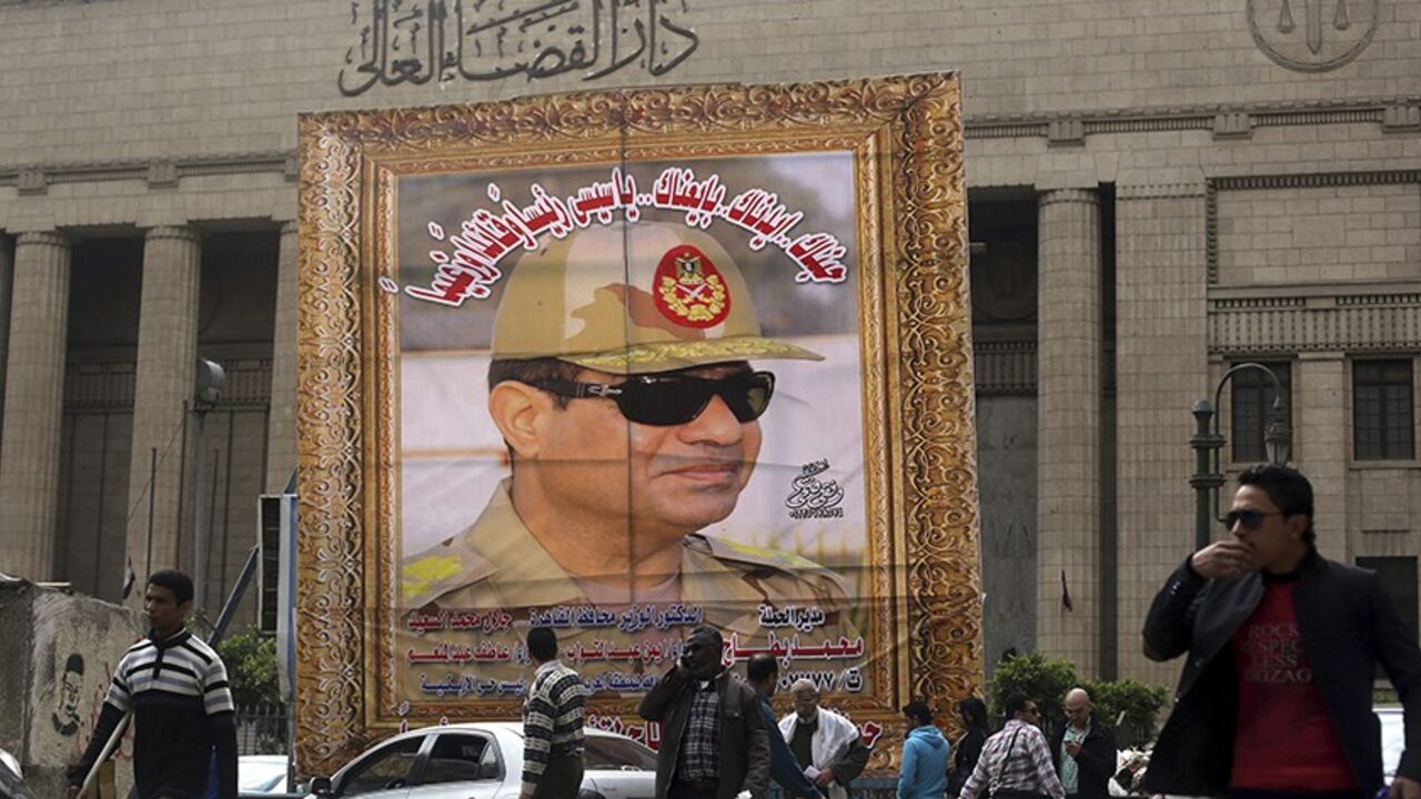 EGYPT People walk past a huge banner for Egypt's army chief, Field Marshal Abdel Fattah al-Sisi in front of the High Court of Justice in downtown Cairo, March 13, 2014. Cairo's souvenir shops and street stands are filled with memorabilia celebrating al-Sisi. Egypt is pushing ahead with an army-backed plan for political transition, with presidential and parliamentary elections due to take place within months. Sisi is widely expected to announce his presidential bid and win easily. Poster reads, "We love and suppor
