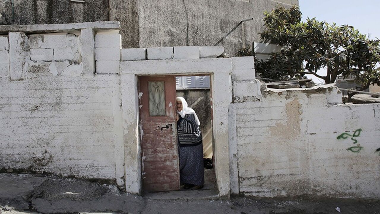 ISRAEL-PALESTINIANS/JERUSALEM A Palestinian woman stands at the entrance to her house in the Shuafat refugee camp in the West Bank near Jerusalem November 26, 2013. Marooned behind the wall, Israel's controversial barrier, the Shuafat refugee camp reveals the state's uneven treatment of Arab and Jewish neighbourhoods, creating a de facto partition of Jerusalem, which is the epicentre of the Middle East conflict. Picture taken November 26, 2013. REUTERS/Ammar Awad (WEST BANK - Tags: POLITICS SOCIETY) - RTX16PGL
