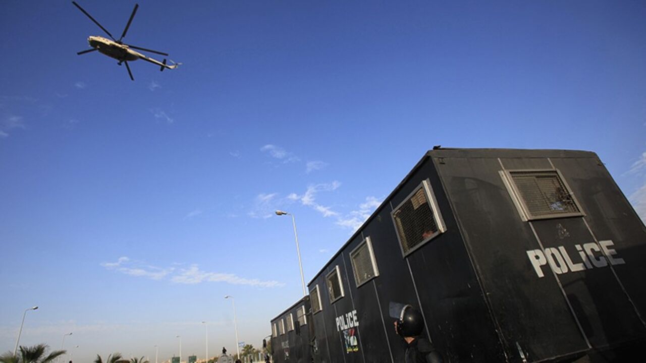 EGYPT-MURSI/DELAY A military helicopter flies over riot police standing guard outside a police academy, where ousted Egyptian President Mohamed Mursi's second trial session was due to take place, on the outskirts of Cairo January 8, 2014. Mursi's arrival at the Cairo court where he was due to stand trial on Wednesday was delayed by poor weather, state TV reported. Mursi was due to be flown to the Cairo police academy where the court was due to convene. Mursi is currently in a jail near the Mediterranean city of Alexandria.
