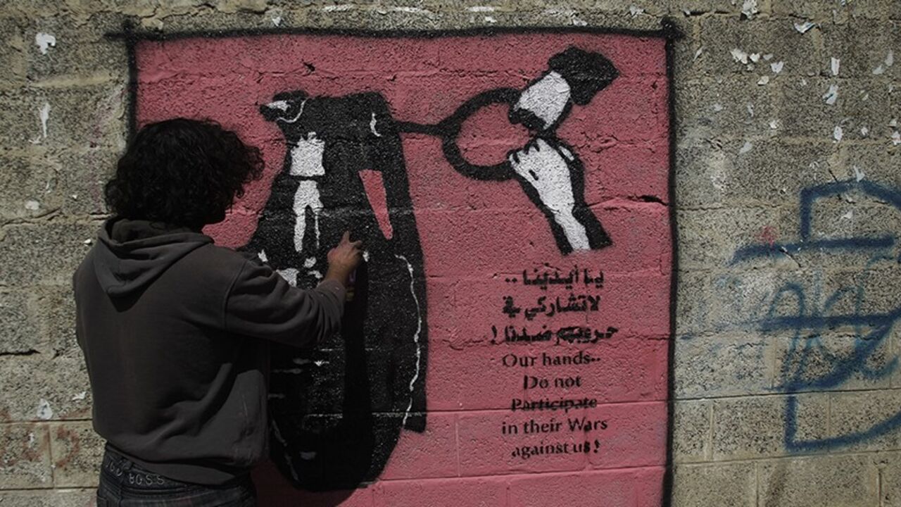 YEMEN/ Artist Murad Subai paints a graffiti depicting a grenade on a street in Sanaa January 9, 2014. The paint is part of a graffiti campaign against armed conflicts in Yemen. REUTERS/Khaled Abdullah (YEMEN - Tags: POLITICS SOCIETY CIVIL UNREST) - RTX177LB