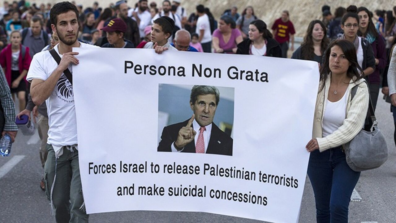 PALESTINIANS-ISRAEL/ Right-wing Israelis hold a banner depicting U.S Secretary of State John Kerry as they march during a rally in E1, an area in the West Bank near Jerusalem February 13, 2014. Thousands of right-wing Israelis took part in the rally on Thursday in E1, a geographically sensitive area which connects the two parts of the Israeli-occupied West Bank outside Arab suburbs of East Jerusalem, calling for Israeli building in the area which Palestinians seek for a contiguous future state. REUTERS/Baz Ratner (WEST BANK - T