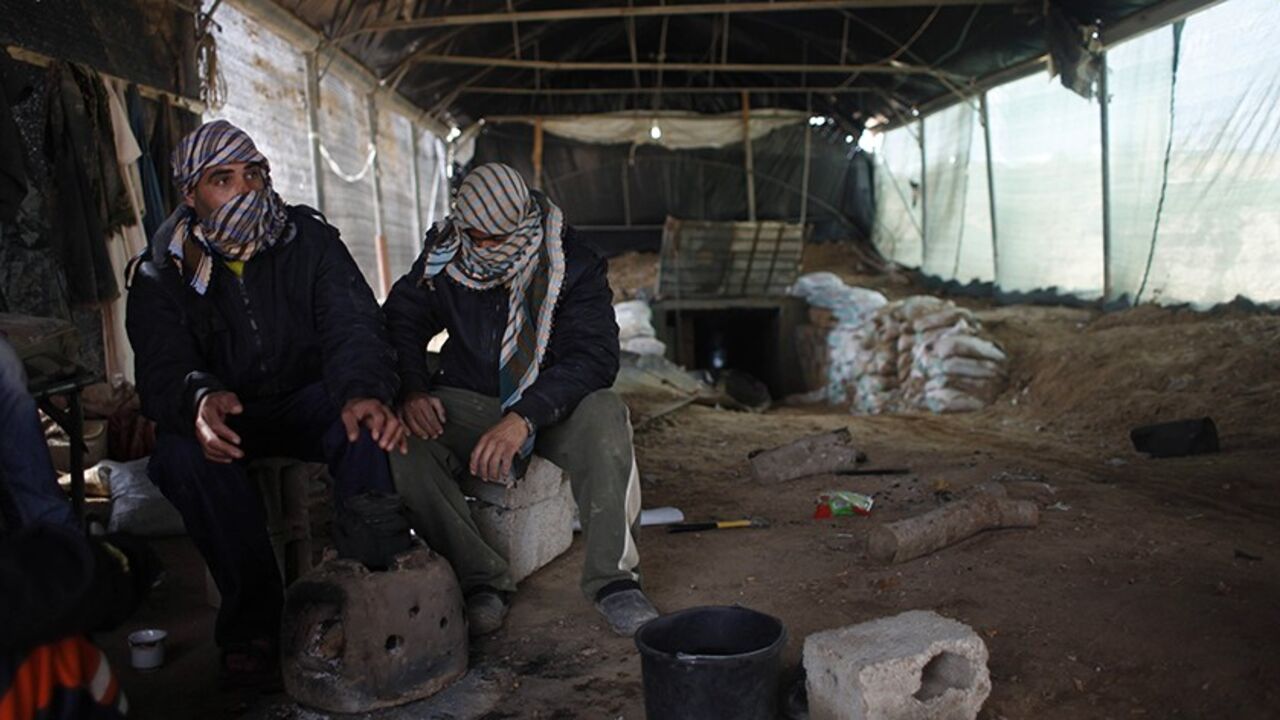Tunnel workers sit outside a smuggling tunnel on the border between Egypt and the southern Gaza Strip February 17, 2014. Voices of construction workers and the noise from their tools used to ring out in Gaza's streets. Now hulks of unfinished buildings stand in eerie silence, and the idle builders are left to worry how to make ends meet. An Egyptian-Israeli blockade on Gaza, run by the Hamas Islamist movement, has left industry and construction gasping for resources, pushing unemployment to dizzying heights