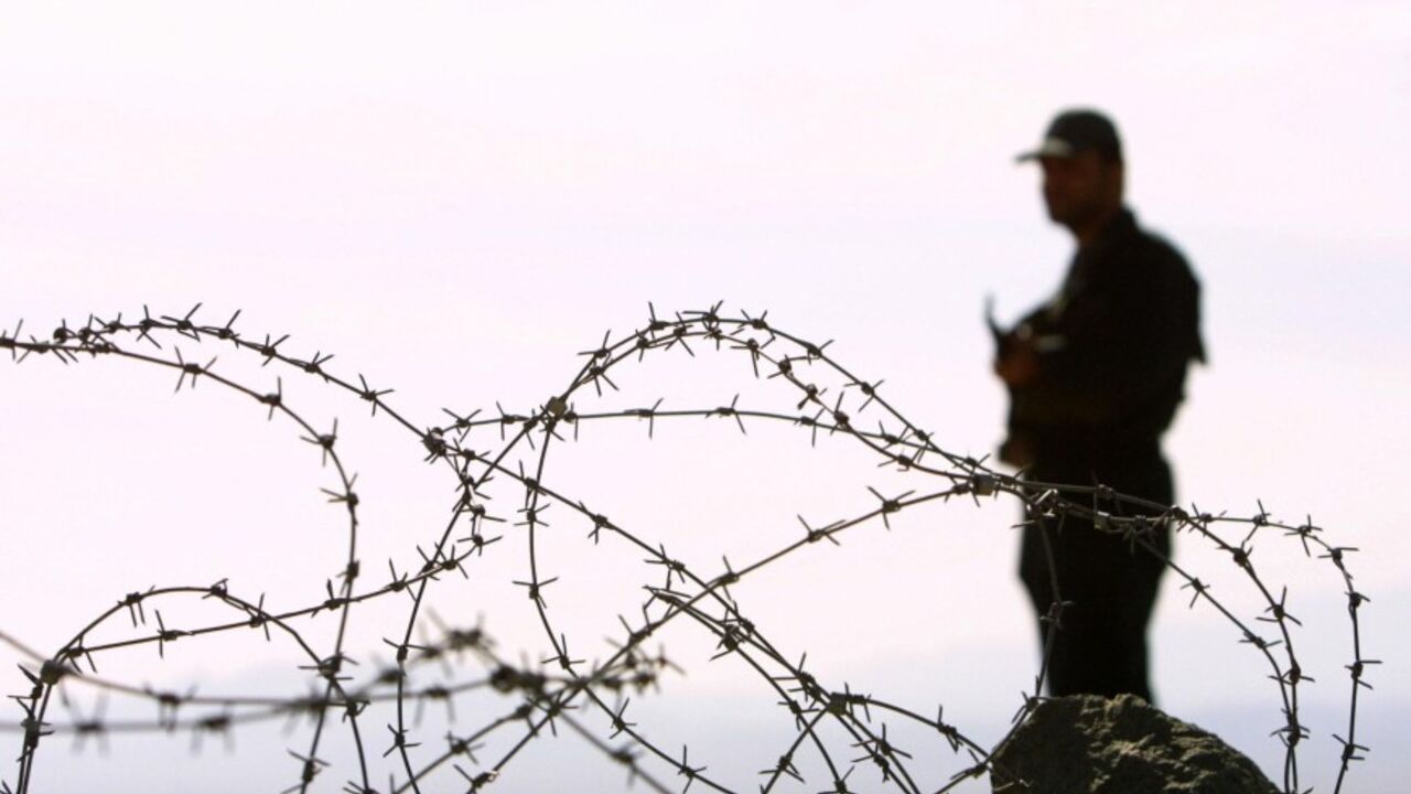 NIC2003120339787 MIRJAVEH, IRAN: An Iranian soldier stands guard on a mound built to prevent drug trafficking 02 December 2003 in the Mirjaveh point where the borders of Iran, Afghanistan and Pakistan meet. But despite the bulldozed trenches and mounds of dust and the string of machine-gun posts ought to be enough to put off all but the most suicidal drug traffickers hoping to enter Iran, officials taking the UN anti-drugs tsar on the tour admitted they were losing the war on drugs. AFP PHOTO/Behrouz MEHRI (Photo cre