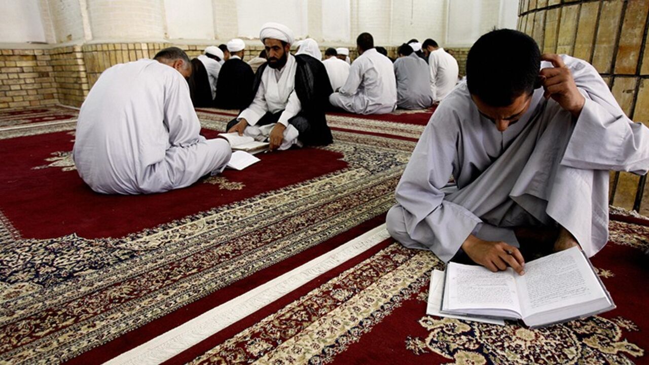Nic95594 NAJAF, IRAQ: An Iraqi Shiite scholar (2nd L) lectures a student while another one (R) reviews his lesson at a religious school for clerics, known in Arabic as Haouza, in the holy city of Najaf, 160 kms (100 miles) south of Baghdad, 05 August 2006. The teaching method at the clerical school in Najaf has not radically changed since its establishment in 1056 AD, with the exception of adding natural sciences subjects to the curriculum. AFP PHOTO/ALI AL-SAADI (Photo credit should read ALI AL-SAADI/AFP/Getty I