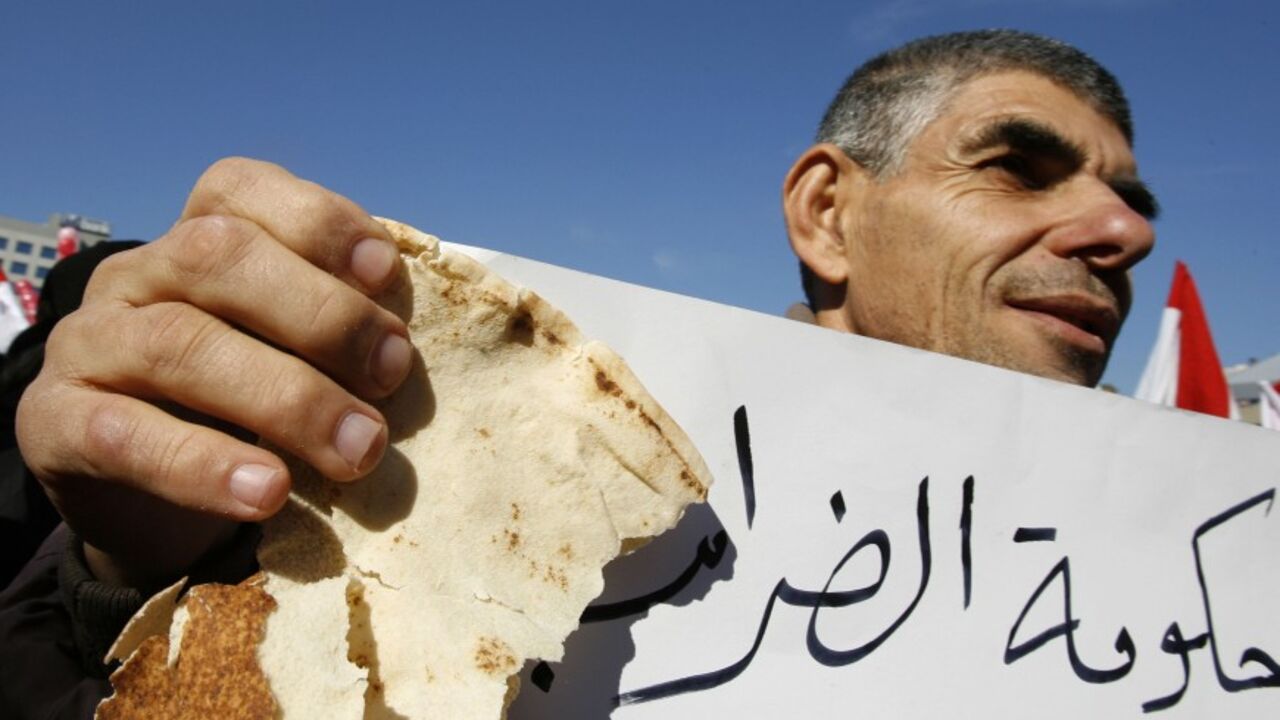 LEBANON-GOVERNMENT/ A protester carries a piece of bread and an anti-government banner during a Hezbollah-backed protest against the government's economic reform programme outside the tax office in Beirut January 9, 2007. REUTERS/Jamal Saidi (LEBANON) - RTR1L0JU