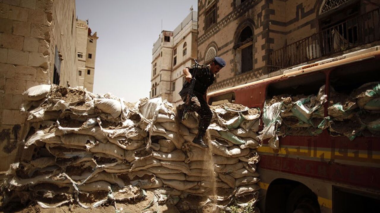 YEMEN/ A police trooper jumps over a barricade of sand bags, erected by tribal militants loyal to the powerful al-Ahmar family during last year's fighting with security forces, in Sanaa May 28, 2012. A military committee, set up under a Gulf Cooperation Council peace deal signed in Saudi Arabia in November, continued on Monday the breaking down of militant fortifications that have been set up in the Yemeni capital during protests against former President Ali Abdullah Saleh. REUTERS/Khaled Abdullah (YEMEN - Tags: P