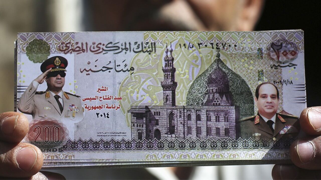 EGYPT/ Al Hag Asaad, 62, a street vendor selling Abdel Fattah al-Sisi themed souvenirs, shows a fake 200 Egyptian pound with a picture of al-Sisi at a bazaar in Tahrir square in central Cairo, March 13, 2014. Cairo's souvenir shops and street stands are filled with memorabilia celebrating the popular head of the armed forces, Field Marshal al-Sisi. Egypt is pushing ahead with an army-backed plan for political transition, with presidential and parliamentary elections due to take place within months. Sisi is widely