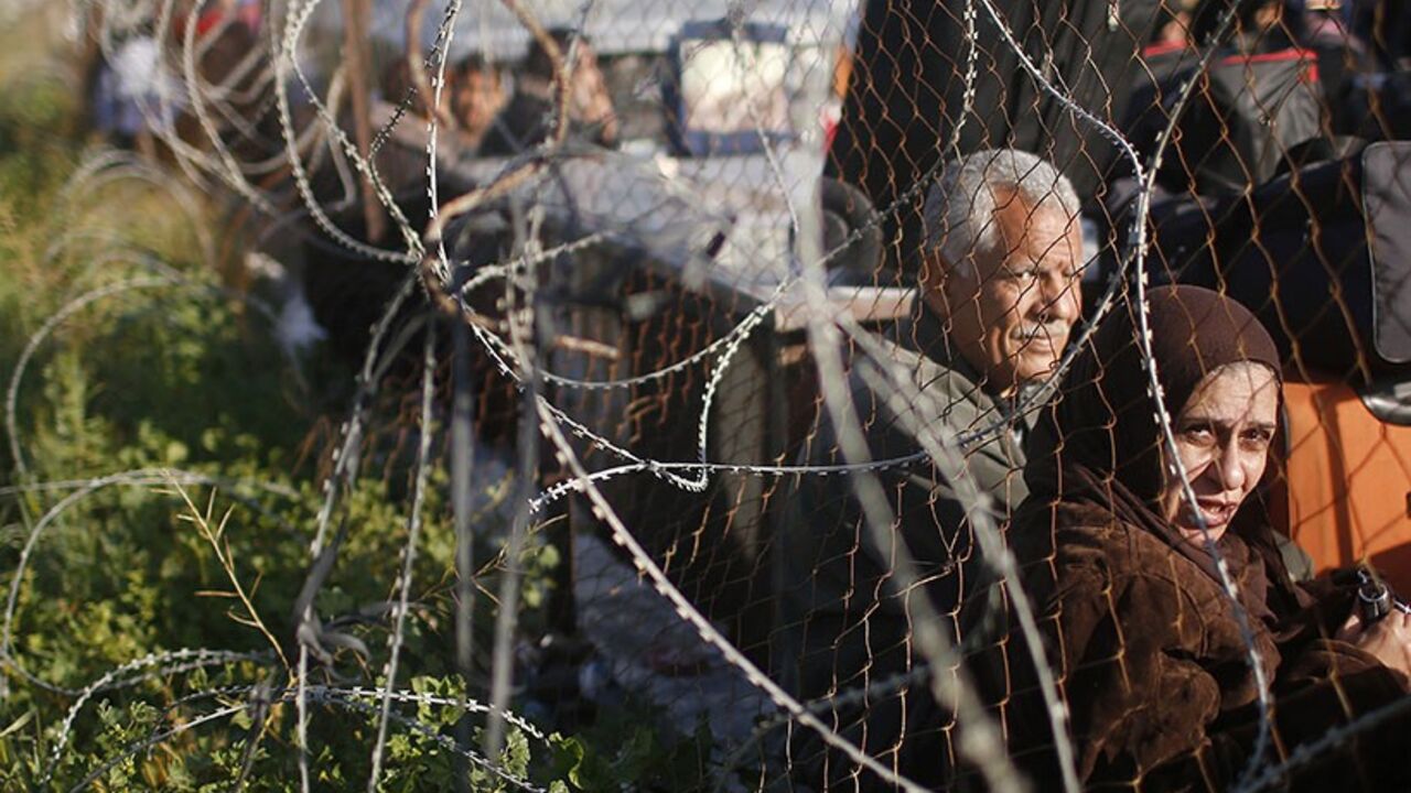 PALESTINIAN-EGYPT/ Palestinians hoping to cross into Egypt wait behind a barbed wire fence at the Rafah crossing between Egypt and the southern Gaza Strip March 29, 2014. Egyptian authorities partially reopened Rafah border crossing, Gaza's main window to the world, on Saturday for three days after 50 days of its closure, Palestinian border officials said. Since the overthrow of Egyptian President Mohamed Mursi in July 2013, the authorities have largely kept the crossing closed, only opening it partially for limited periods o