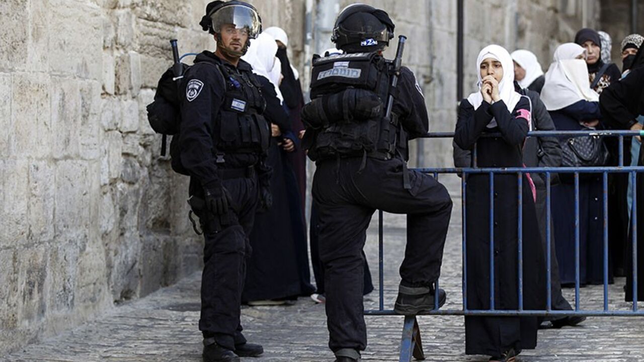 PALESTINIANS-ISRAEL/VIOLENCE A Palestinian woman looks on as Israeli policemen prevent people from entering the compound which houses al-Aqsa mosque and is known to Muslims as Noble Sanctuary and to Jews as Temple Mount, in Jerusalem's Old City April 16, 2014. Israeli riot police entered one of Jerusalem's most revered and politically sensitive religious compounds on Wednesday to disperse rock-throwing Palestinians opposed to any Jewish attempts to pray there. REUTERS/Ammar Awad (JERUSALEM - Tags: POLITICS CIVIL UNREST RELIGION) - RTR3
