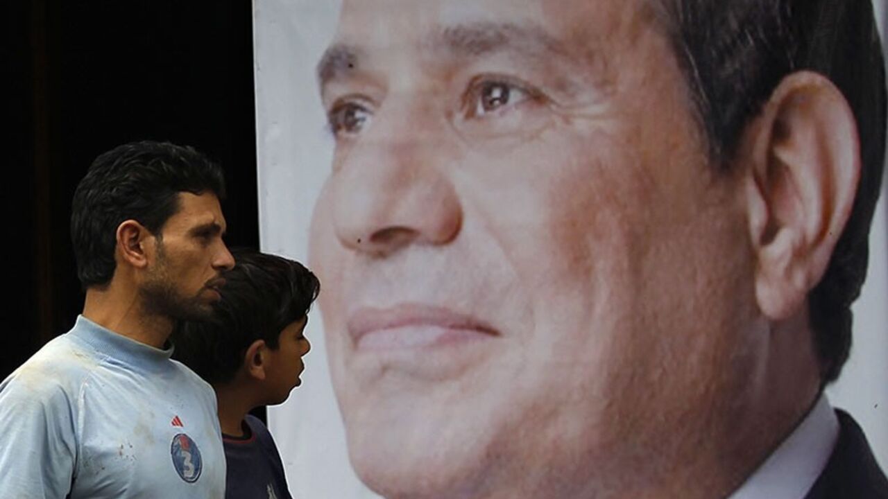 EGYPT/ People walk past a poster of presidential candidate and former army chief Abdel Fattah al-Sisi at one of his campaign headquarters in central Cairo April 16, 2014. Egyptians will vote on May 26-27 in a presidential election where Abdel Fattah al-Sisi is expected to win easily. REUTERS/Amr Abdallah Dalsh (EGYPT - Tags: POLITICS ELECTIONS) - RTR3LLFJ