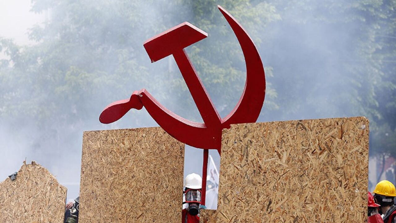 TURKEY-PROTESTS/ A protester holds a hammer and a sickle sign as he and others shield themselves from police during a May Day demonstration in Istanbul May 1, 2014. Turkish police fired water cannon and tear gas on Thursday to prevent hundreds of protesters from defying a ban on May Day rallies and reaching Istanbul's central Taksim Square, the focal point of weeks of protests last summer. REUTERS/Murad Sezer (TURKEY - Tags: POLITICS CIVIL UNREST) - RTR3NDAF