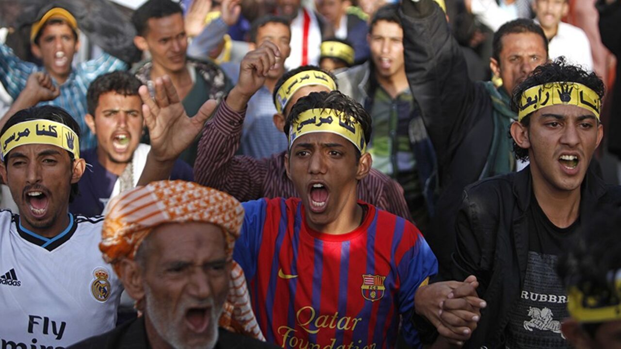 YEMEN/ Pro-democracy protesters, some of whom belong to Yemen's Muslim Brotherhood, and are supporters of Egypt's ousted President Mohamed Mursi, shout slogans as they demonstrate to demand that Yemen's former president Ali Abdullah Saleh be put on trial, in Sanaa September 25, 2013. Headbands read, "Rabaa, We are all Mursi". REUTERS/Khaled Abdullah (YEMEN - Tags: POLITICS CIVIL UNREST) - RTX13ZD0
