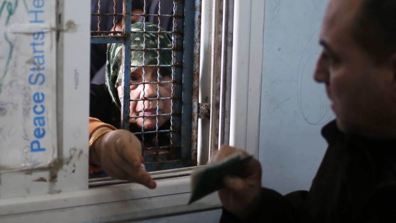 PALESTINIAN-GAZA/UN A Palestinian woman presents her identification as she waits to receive food supplies from a United Nations food distribution centre in Gaza City December 19, 2013. Almost a million people are expected to need food aid in the Gaza Strip next year, a U.N. agency said on Wednesday as it appealed for $95 million from donors. REUTERS/Mohammed Salem (GAZA - Tags: POLITICS SOCIETY) - RTX16O8Y