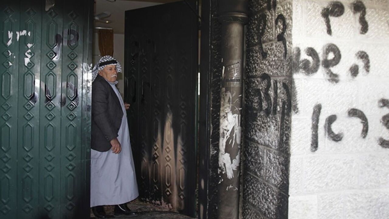 ISRAEL-PALESTINIANS/MOSQUE A Palestinian man stands near a door and wall of a mosque which were vandalised in the West Bank village of Deir Istiya, near the Jewish settlement of Ariel January 15, 2014. The mosque in the north of the Israeli-occupied West Bank was partly set on fire on Wednesday, in what Palestinians residents said was an attack by Jewish settlers living nearby. The main gate of the mosque and some of the carpeting inside were charred by the flames. Graffiti in Hebrew, reading "Revenge for spilled blood" and "Arabs Ou
