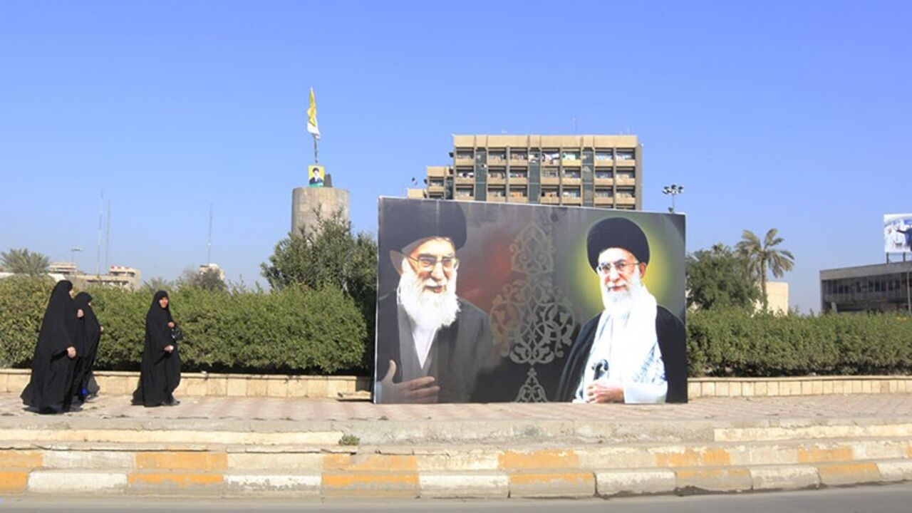 IRAQ-VIOLENCE/ Iraqi women walk towards a poster depicting images of Shi'ite Iran's Supreme Leader Ayatollah Ali Khamenei at al-Firdous Square in Baghdad February 12, 2014. An Iraqi daily newspaper stopped publishing after two bombs were planted in the entrance to its headquarters in Baghdad on Monday and after threats from an Iranian-backed Shi'ite militia. Editors and reporters at Assabah AlJadeed said they had received death threats from the influential Asaib al-Haq militia in response to what it had described as an "i