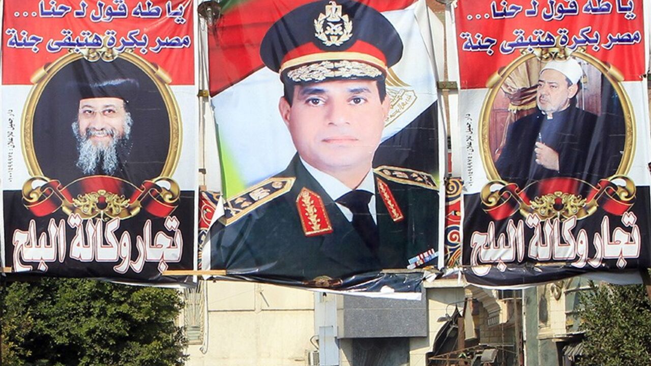 EGYPT-ENERGY/ People walk near banners of Egypt's army chief, Field Marshal Abdel Fattah al-Sisi (C), with Coptic and Islamic leaders Grand Sheikh of Al-Azhar Ahmed al-Tayeb (R) and Pope Tawadros II (L) of the Coptic Orthodox Church in Cairo February 19, 2014. Sisi, won vast popularity by crushing the Muslim Brotherhood, but even a man seen by his followers as invincible may be unable to fix the mess in the politically sensitive energy sector. Sisi, who toppled Islamist leader Mohamed Mursi in July and promised to bring