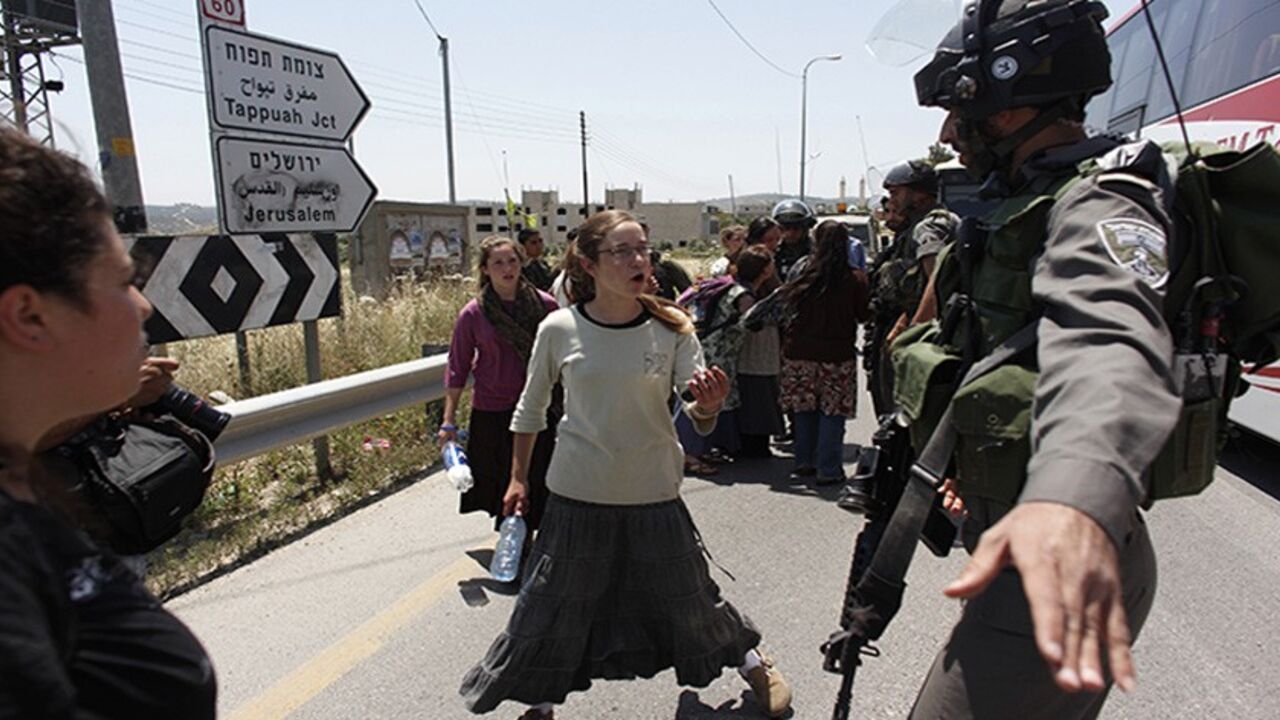PALESTINIANS-ISRAEL/ Israeli border police officers try to prevent Jewish settlers from interrupting Palestinian traffic after a stabbing attack, near the West Bank Jewish settlement of Yitzhar near Nablus April 30, 2013. A Palestinian man stabbed and shot dead an Israeli settler in the occupied West Bank on Tuesday, the Israeli ambulance service and police said. REUTERS/Nir Elias (WEST BANK - Tags: POLITICS CIVIL UNREST) - RTXZ4N7
