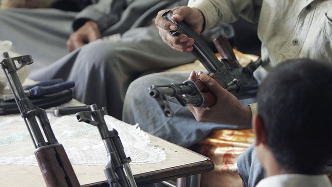A buyer inspects a weapon inside a shop selling firearms in Baghdad March 2, 2006. Fearful of sectarian attacks since the bombing of a Shi'ite shrine on February 22, Iraqis are barricading homes and stocking up on weapons in a country already awash with guns. Picture taken March 2, 2006. REUTERS/Faleh Kheiber - RTR16W8K