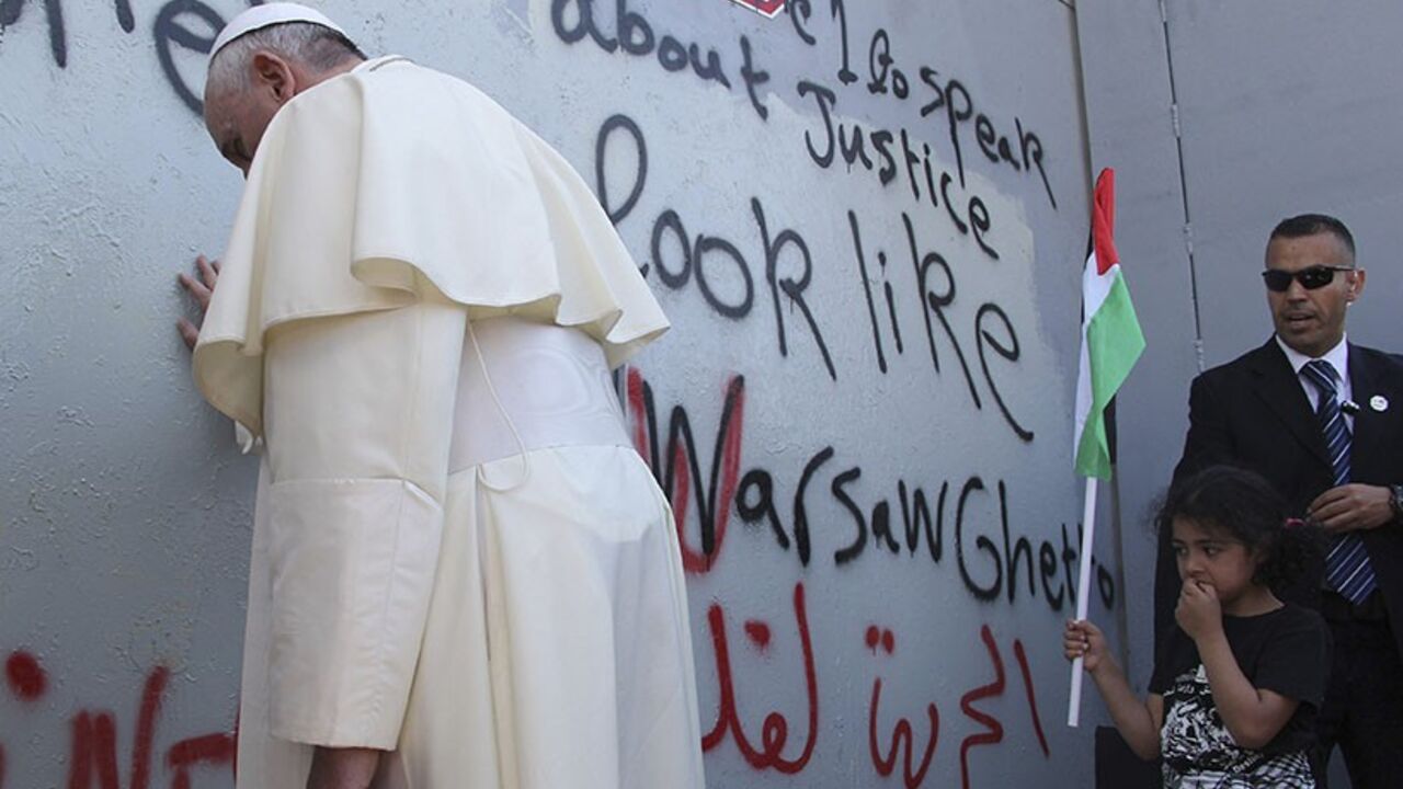 POPE-HOLYLAND/ Pope Francis touches the wall that divides Israel from the West Bank, on his way to celebrate a mass in Manger Square next to the Church of the Nativity in the West Bank city of Bethlehem May 25, 2014. Pope Francis made a surprise stop at the hulking wall Palestinians see as a symbol of Israeli oppression on Sunday, minutes after begging both sides to end a conflict that he said was no longer acceptable. REUTERS/Mheisen Amareen (WEST BANK - Tags: RELIGION POLITICS TPX IMAGES OF THE DAY) - RTR3QRA8
