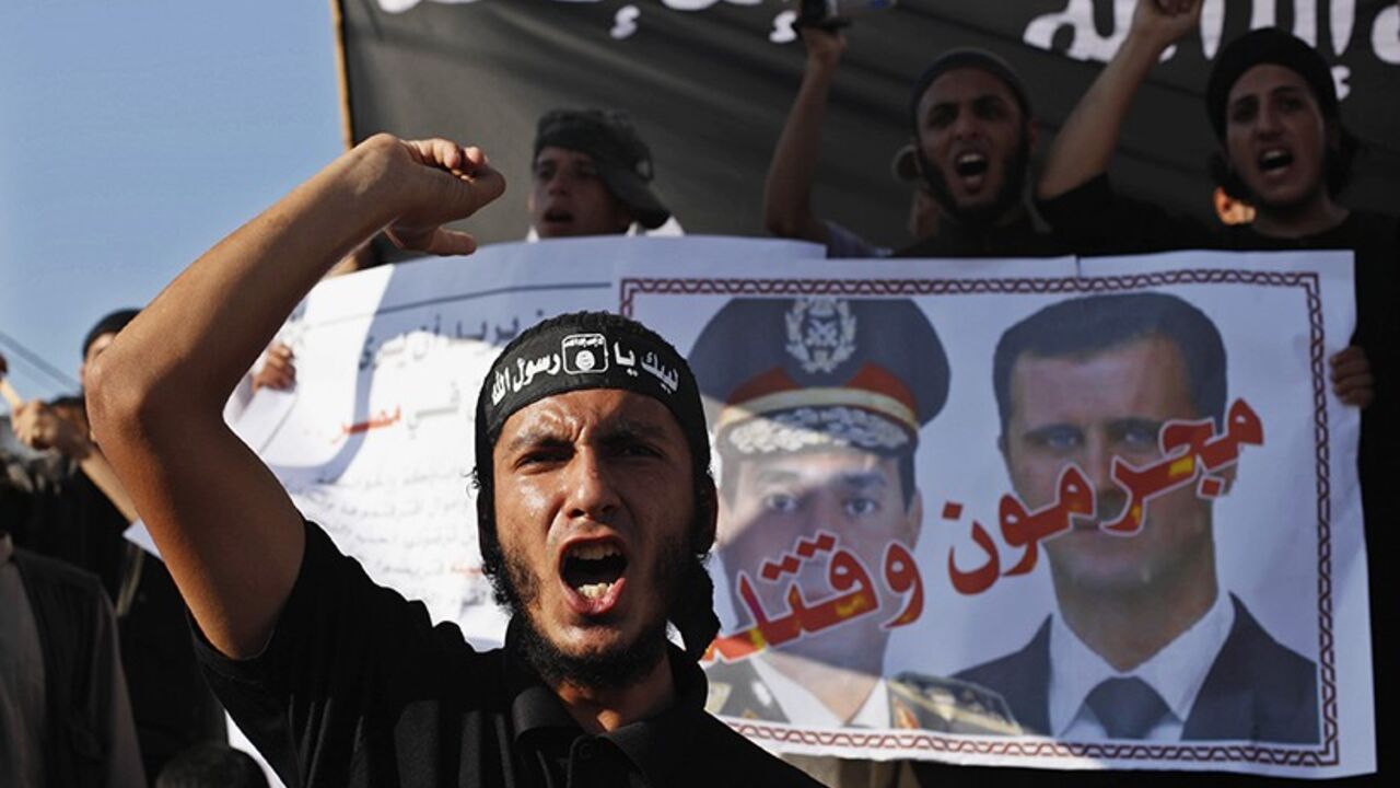 PALESTINIANS-EGYPT/ A Palestinian Salafist shouts slogans in front of a poster depicting Syria's President Bashar al-Assad (R) and Egypt's army chief General Abdel Fattah al-Sisi with the Arabic words that read "criminals and murderers", during a rally in protest of what they say are recent massacres committed against Syrian and Egyptian people, in Rafah in the southern Gaza Strip August 22, 2013. REUTERS/Ibraheem Abu Mustafa (GAZA - Tags: POLITICS CIVIL UNREST TPX IMAGES OF THE DAY) - RTX12TC6