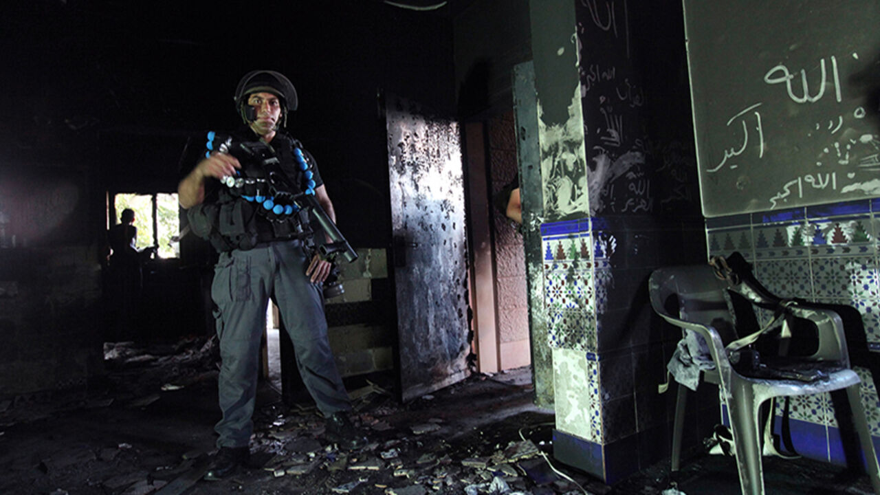 To match feature PALESTINIANS-ISRAEL/ARABS An Israeli police officer stands inside a burnt mosque in the Bedouin village of Tuba-Zangariya in northern Israel October 3, 2011, before the arrival of Israel's President Shimon Peres. They strike in the dead of night, setting fire to mosques and daubing their walls with "Price Tag" graffiti, the defiant slogan of Israeli settlers waging a vigilante campaign branded as "un-Jewish" by President Shimon Peres. The "price-taggers" have vowed to avenge any move by Israeli authorities to uproot settlement out