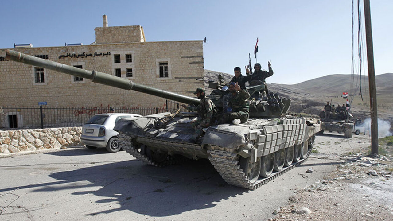 Soldiers loyal to President al-Assad gesture from tank, as they pass Mar Bacchus Sarkis monastery, in Maloula village, northeast of Damascus Soldiers loyal to Syria's President Bashar al-Assad gesture from their tank, as they pass Mar Bacchus Sarkis monastery, in Maloula village, northeast of Damascus, after taking control of the village from rebel fighters April 14, 2014. REUTERS/Khaled al-Hariri (SYRIA - Tags: MILITARY POLITICS CONFLICT CIVIL UNREST TPX IMAGES OF THE DAY) - RTR3L92W