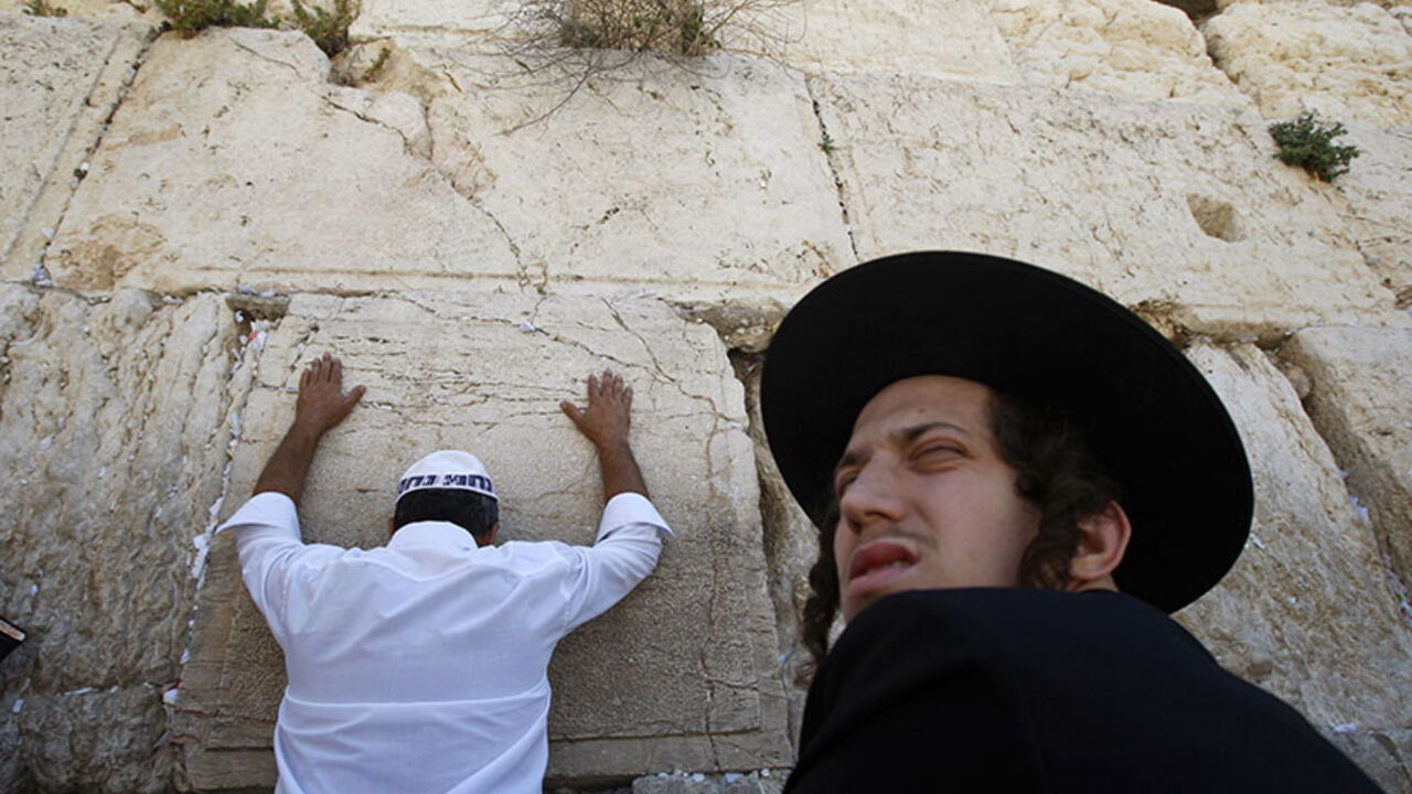 Jewish worshipper prays as Ultra-Orthodox Jew sits in front of the Western Wall in Jerusalem A Jewish worshipper prays as an ultra-Orthodox Jew sits in front of the Western Wall, Judaism's holiest prayer site, in Jerusalem's Old City May 28, 2009. On Thursday Jews mark Shavuot, the annual celebration of God's handing down of the Law (the Torah) to Moses at Mount Sinai in biblical times, according to Jewish tradition. REUTERS/Baz Ratner (JERUSALEM RELIGION) - RTXOVZB