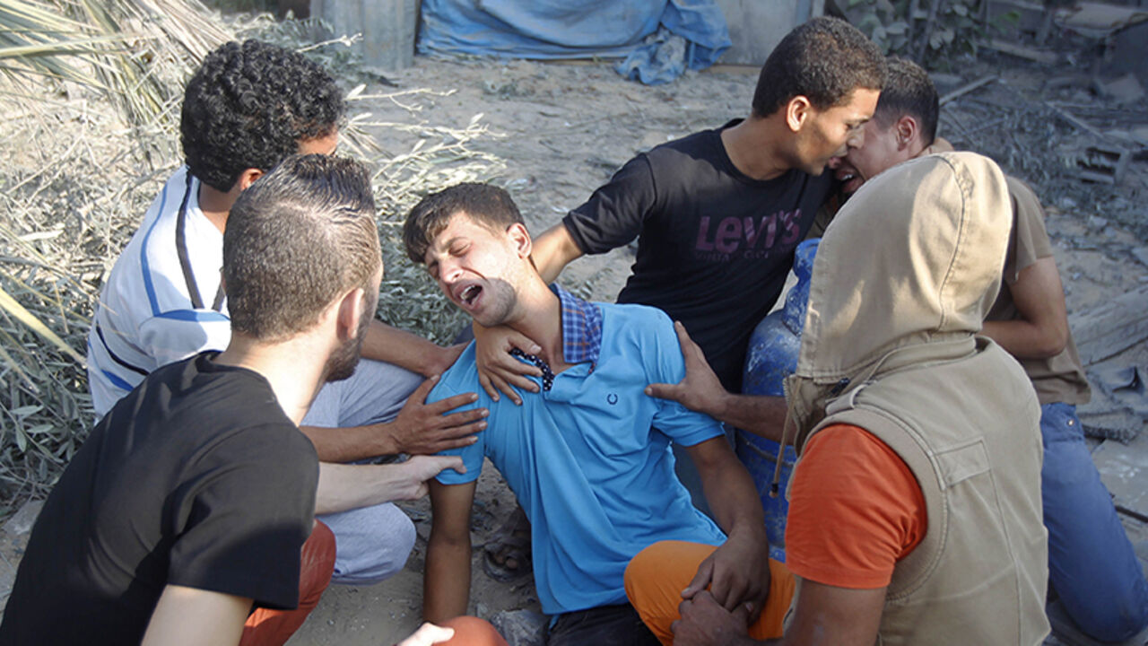 PALESTINIAN-ISRAEL-GAZA-CONFLICT Palestinian relatives mourn for victims of the Duheir family, near the rubble of their home, after it was destroyed by an Israeli air strike in Rafah on July 29, 2014, in the southern of Gaza strip. Bloodshed in war-torn Gaza surged with dozens more Palestinians killed as the conflict raged into a fourth week and Iran accused Israel of genocide in the tiny enclave. AFP PHOTO/ SAID KHATIB (Photo credit should read SAID KHATIB/AFP/Getty Images)