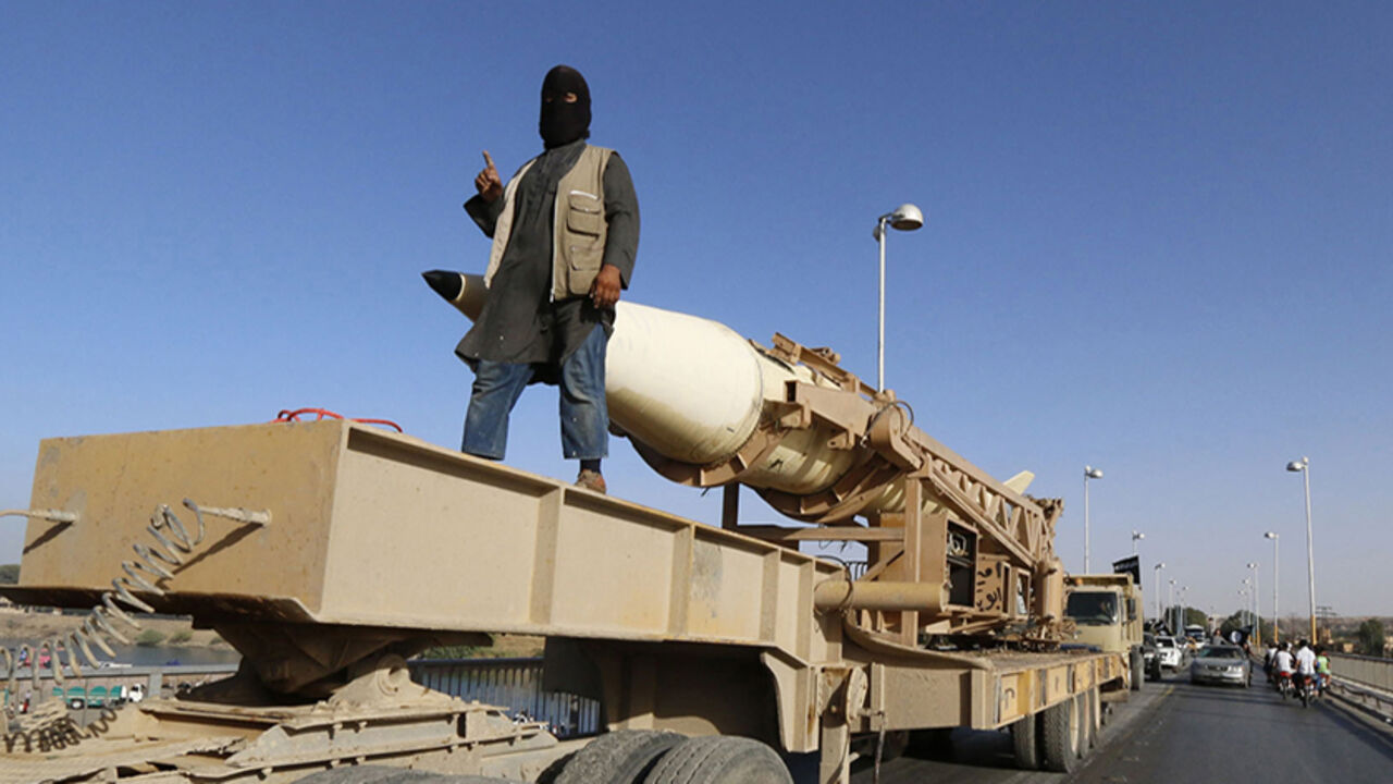 A militant Islamist fighter gestures as he takes part in a military parade along the streets of Syria's northern Raqqa province June 30, 2014. The fighters held the parade to celebrate their declaration of an Islamic "caliphate" after the group captured territory in neighbouring Iraq, a monitoring service said. The Islamic State, an al Qaeda offshoot previously known as Islamic State in Iraq and the Levant (ISIL), posted pictures online on Sunday of people waving black flags from cars and holding guns in th