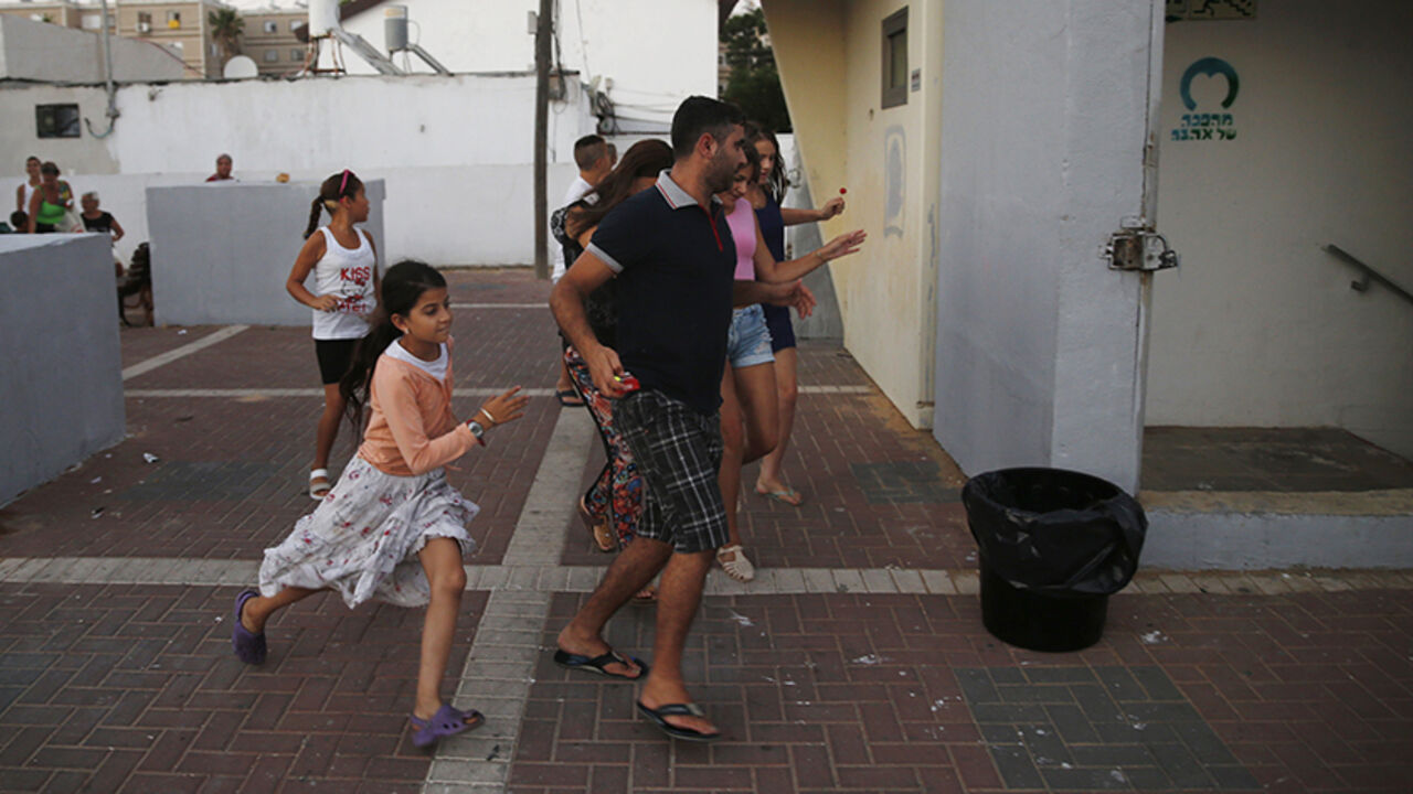 Israelis take cover in a bomb shelter as a siren sounds warning of incoming rockets in Ashkelon Israelis run towards a bomb shelter as a siren sounds warning of incoming rockets in the southern city of Ashkelon July 9, 2014. Israeli air strikes shook Gaza every few minutes on Wednesday, and militants kept up rocket fire at Israel's heartland in intensifying warfare that Palestinian officials said has killed at least 44 people in the Hamas-dominated enclave. REUTERS/Baz Ratner (ISRAEL - Tags: POLITICS CIVIL UNREST) - RTR3XVKO